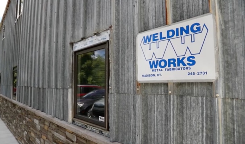 Wooden building with blue welding works sign