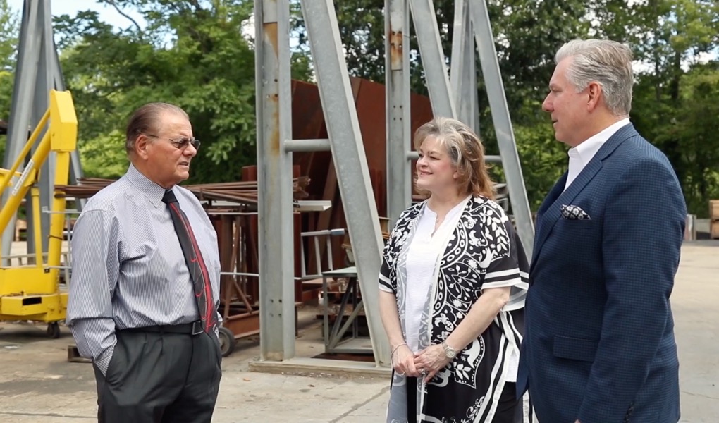 two men and a woman standing outside in industrial setting