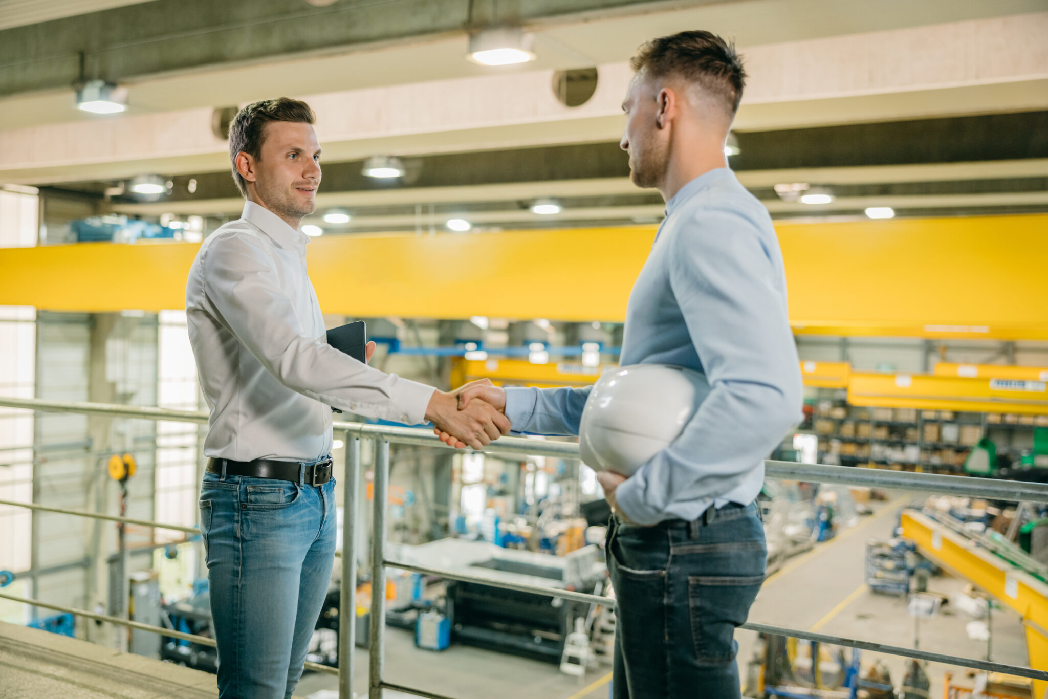 Two engineers shaking hand at manufacturing plant